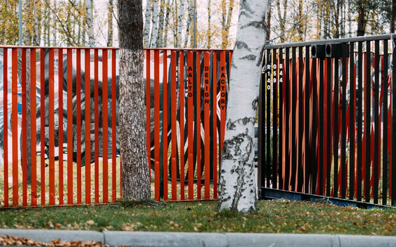 A red and black striped container with 'Aalto Design Factory' written on it, next to white birch trees.