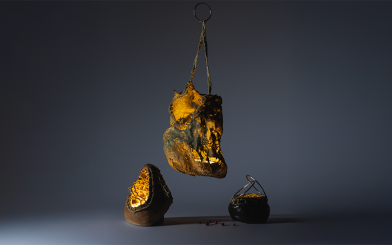 Three abstract, textured objects with glowing interiors, one hanging and two sitting on a dark surface.
