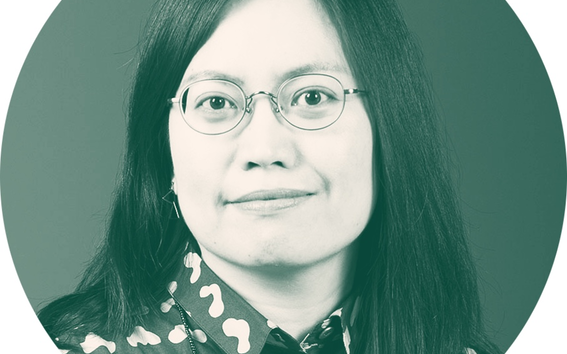 Person with long hair wearing a patterned shirt with abstract shapes.