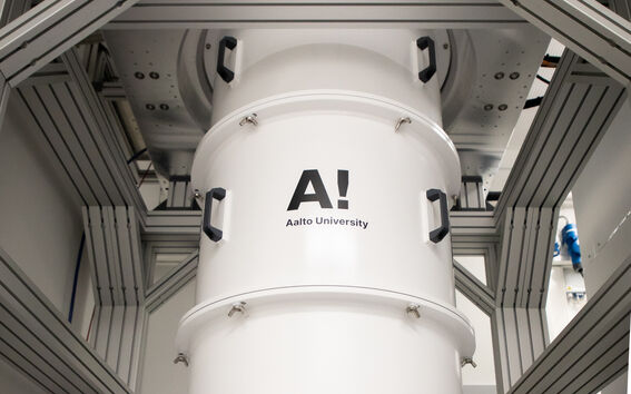 A white cylindrical machine with 'Aalto University' logo in an industrial setting.