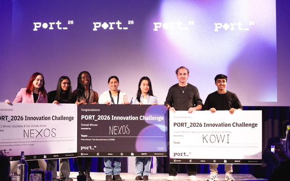 Seven people holding large checks at PORT_2026 Innovation Challenge event. Checks awarded to teams NEXOS and KOWI.