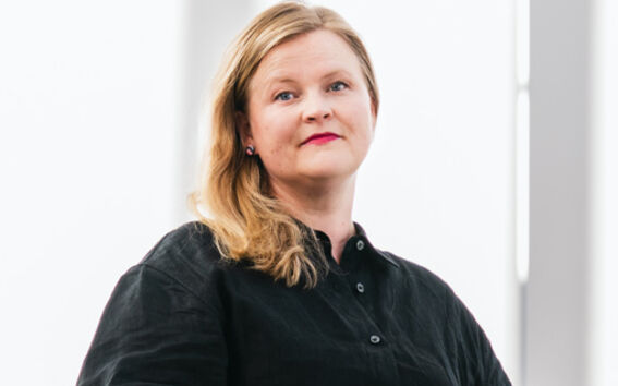 Henkilö, jolla on musta paita, seisoo kaiteen vieressä kirkkaiden ikkunoiden edessä