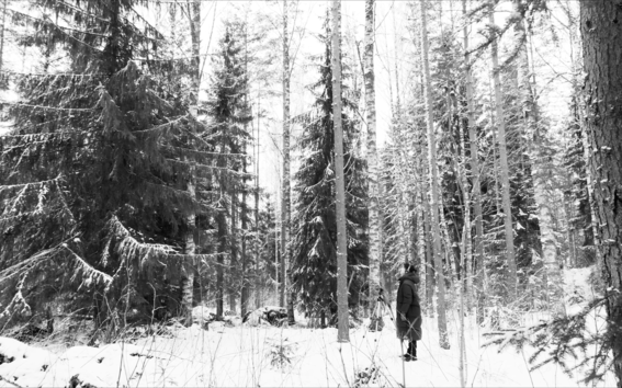 black and white image of a woman standing in a snowy forest