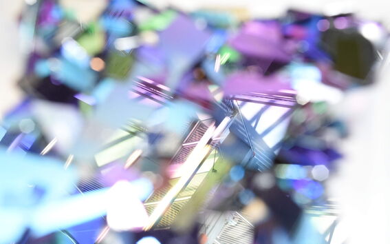 Abstract close-up of prismatic shards reflecting blue, purple and green light with soft geometric shapes