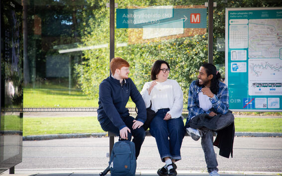 3 people sitting at Aalto University's tram stop