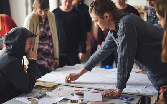 Group of young adults around a table, co-creating with sticky notes in a bright studio