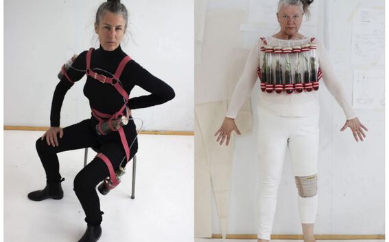 Two women pose in black and white outfits with strapped glass tubes worn as experimental body harnesses.
