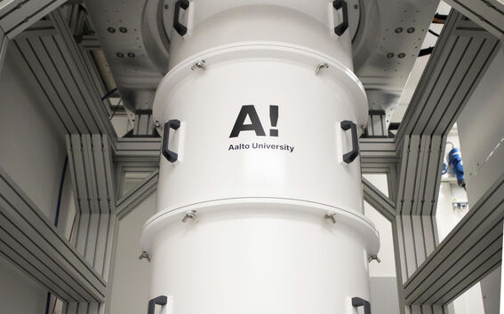 Large white cylindrical lab device in a metal frame, labelled Aalto University