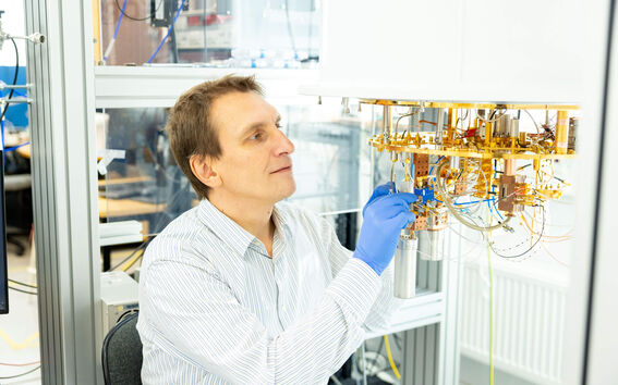 Laboratoriomies säätää monimutkaista kullanväristä laitelaitteistoa sinisissä käsineissä