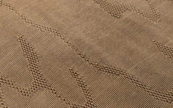 Close-up of brown knitted fabric with raised zigzag pattern across the surface