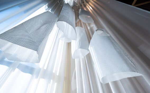 Hanging white fabric lampshades against layered light and dark curtains in soft daylight