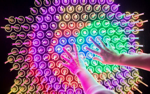 Hands reaching towards different cooured lights in Aalto University Science Lab