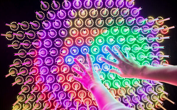 Hands reaching towards different cooured lights in Aalto University Science Lab