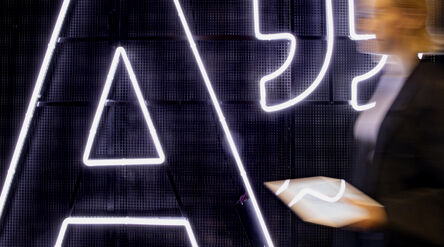 Big Aalto logo light and woman walking past it