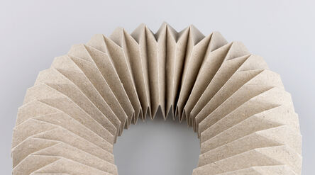A folded origami structure with symmetrical pleats curves across a grey background.