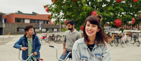 Three students with bicycles in front of Väre building, Aalto University