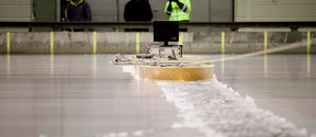 Three researchers using a device on the surface of the ice at Aalto ice tank