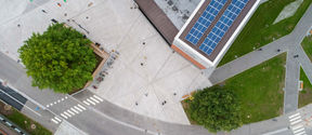 Aerial shot of the Korkeakoulunaukio square. There are solar panels on the Väre roof and trees on the square.
