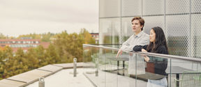 Kaksi opiskelijaa seisomassa Kauppakorkeakoulun kolmannen kerroksen terassilla