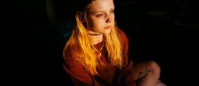Girl sitting in a dark room with light on her face