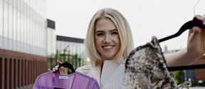 The picture shows Katariina Järvinen on Aalto University campus, holding fashionable pieces of clothes in her hands. 