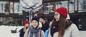 Laughing students in front of Dipoli in the winter, in warm clothing