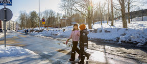 A photo of two young children crossing the street together.