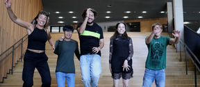 Summer School student group smiling and hopping down the stairs at Aalto's Väre building  