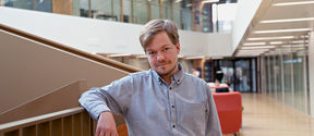 The picture shows Tilman Bauer near the stairs in the School of Business building.