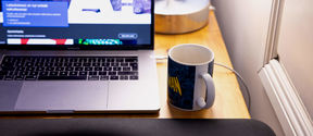 PC on a desk with coffee mug next to it