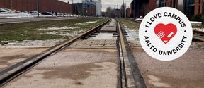 Tram tracks on campus, some snow on the ground, with red-bricked buildings on both sides of the tracks