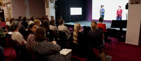 Audience in Aalto Learning Center, Espoo watching two persons on stage at the Green Minds, Healthy Hearts Social Sustainability Symposium, May 30th 2023.