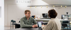 Two students sitting around a table at the School of Business student catereia.