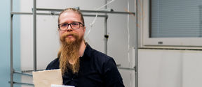 A man holding two small foam boards stands in a lab room.
