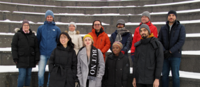 A group of people in coats standing outside on snowy staircase