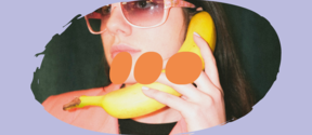 A person holding a banana like a phone with a serious face and sunglasses on. The image is surrounded by an oval-shaped lilac frame with the Sustainability Action Booster orange logo on top of it.