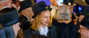 A man with a doctor's hat on celebrating his promotion as a doctor with other doctors