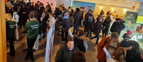 A crowd of people in a lobby where there are roll-ups and branded pop up walls