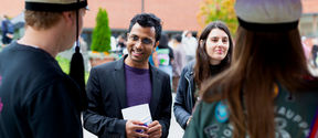 A man and a woman talking to two students wearing teekkari hats