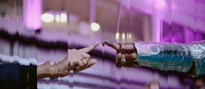 Two hands reaching out to each other, with a reflective background and purple lighting.