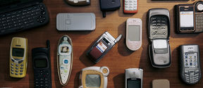 A collection of various old mobile phones laid out on a wooden surface.