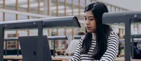 Student typing on a laptop in the library.