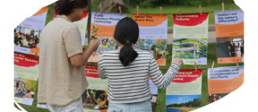 Two people examining event posters hanging outdoors, one in a beige shirt and the other in a stripy top.