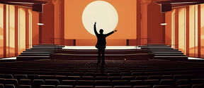 Silhouette of a person with raised arms standing in an empty auditorium facing a large round light on the stage.