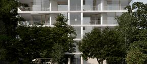 Modern white apartment building with large balconies, surrounded by trees. An elderly person walks with a bicycle.