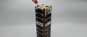 A small satellite with black panels and a red tag that reads 'REMOVE BEFORE FLIGHT' on a grey background.