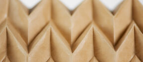 Close-up of brown paper with a zigzag-folded pattern creating a textured geometric design.