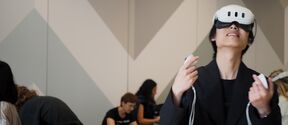 People in a room using virtual reality headsets and controllers. Geometric wall patterns in the background.