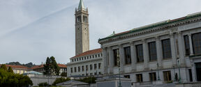 The Berkeley university campus with a tall clock tower and classical buildings, surrounded by green lawns and trees.