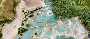 Aerial view of turquoise terraced pools, rocky banks, trees and a small tiled-roof house, with the word “unite!”